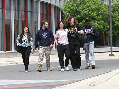 Five students walking on a pathway on the ɫƵ campus.